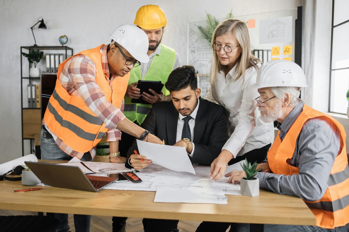 Group architects and engineers sitting at office and working on common project.